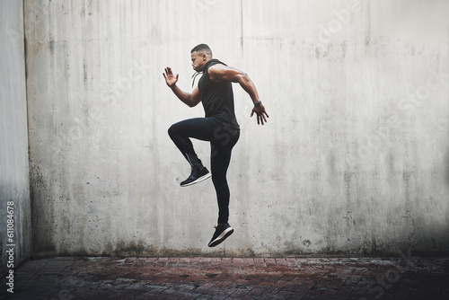 Jump, training and black man running, speed and energy for cardio fitness, workout and sports wellness or body health. Athlete, runner or person exercise on concrete wall, action run or moving in air