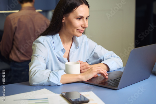 Focused corporate worker working on portable computer during tea break