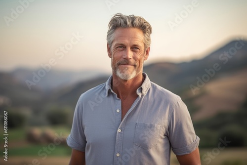 Medium shot portrait photography of a satisfied mature man wearing a casual short-sleeve shirt against a rolling hills background. With generative AI technology