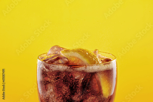 Cola soda glass full of liquid and ice with lemon.