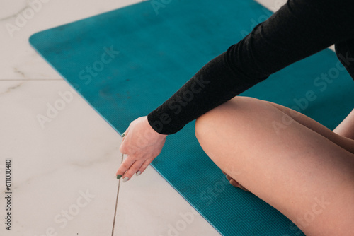 A girl in a black yoga jumpsuit performs yoga asson. Blue yoga mat n the yoga studio