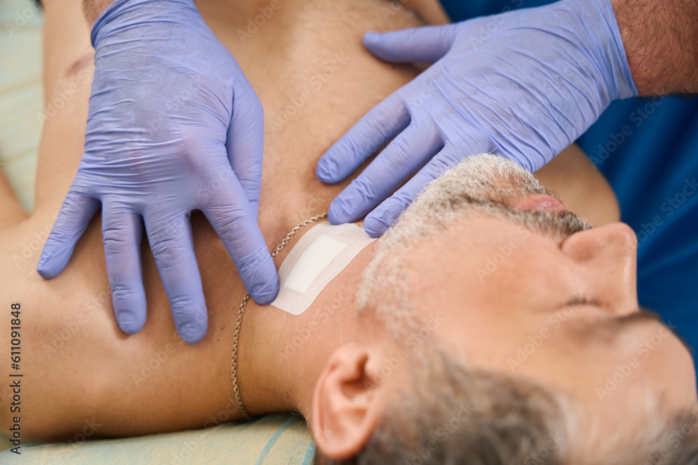 Doctor hands in medical gloves glue patch to injection site Doctor hands in medical gloves glue patch to injection site