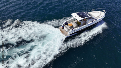 Aerial drone photo of small luxury yacht with wooden deck cruising in high speed deep blue Mediterranean sea