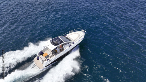 Aerial drone photo of small luxury yacht with wooden deck cruising in high speed deep blue Mediterranean sea