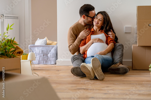Foto A young happy married couple expecting a baby sitting on the floor of their new home after moving in
