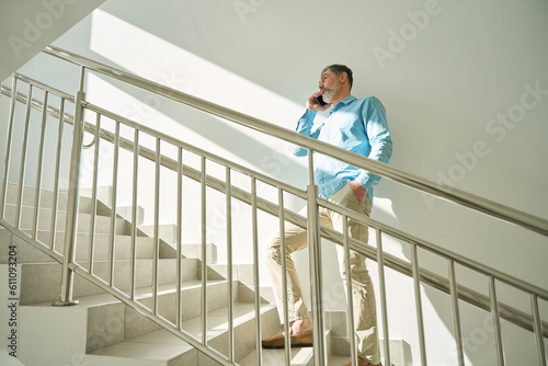 Adult man with beard climbs stairs and talks on phone