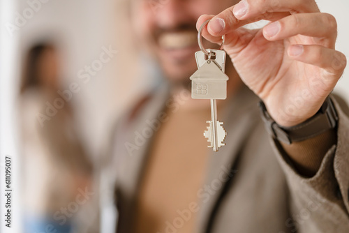 Young couple buying or renting a home or apartment, they are meeting the owner or real estate broker who has the keys; FOCUS on keys