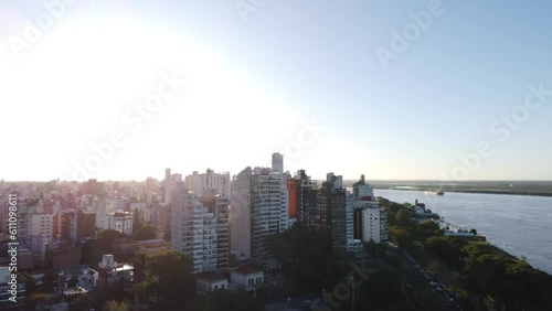 Plano ascendente de la Ciudad de Rosario en Santa Fe, Argentina un día soleado con vista hacia el centro de la ciudad y el Río Paraná volando por sobre el Parque Urquiza photo