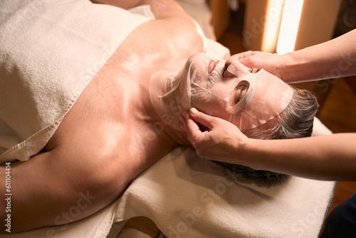 Experienced cosmetician performing anti-aging procedure on mature man © Svitlana