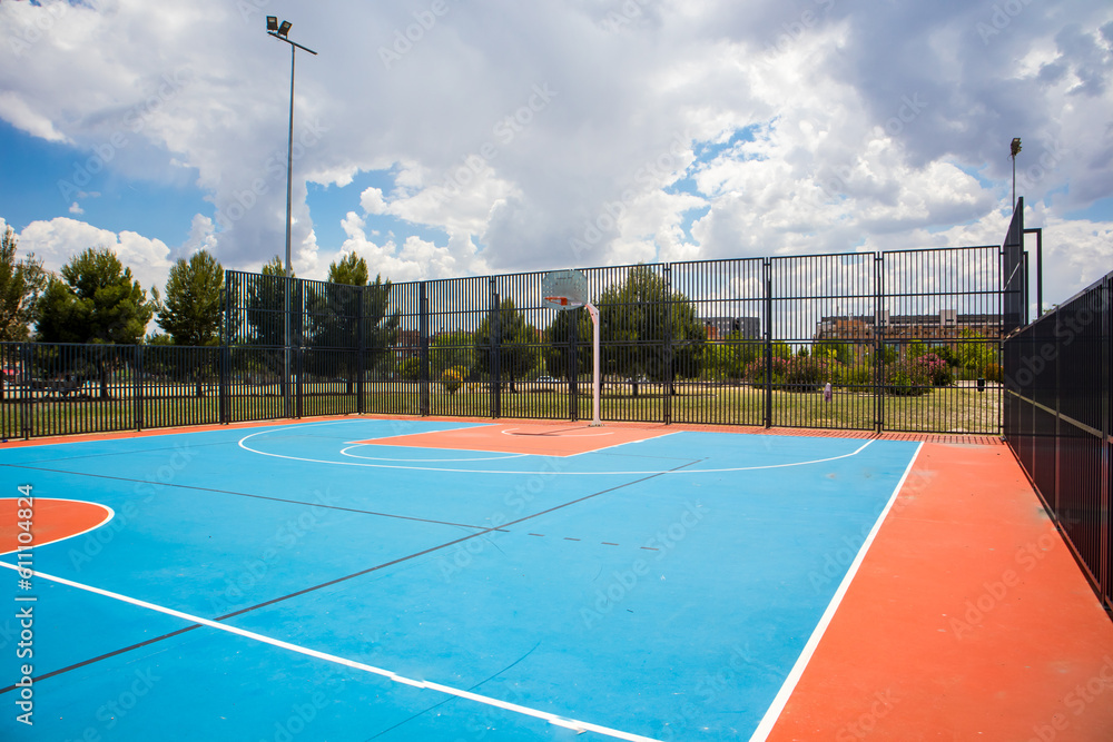 Empty outdoor basketball court in the garden and blue sky. Blue red basketball court for soccer