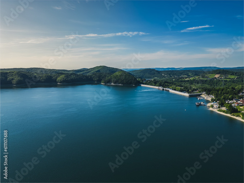 Panoramic view from the drone during sunset, on Lake Solina overlooking the modern gondola lift with a lookout tower over the Solina water dam, in the Polish Bieszczady Mountains, Poland
