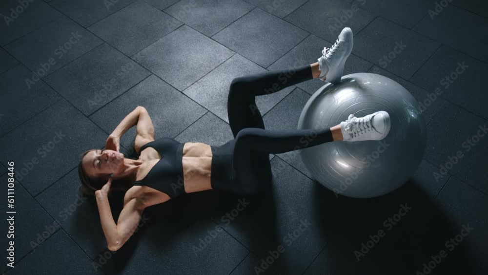 athletic young woman in black sportswear training abs with exercice ball, aerobic exercise in gym. slow motion. top view. High quality 4k footage