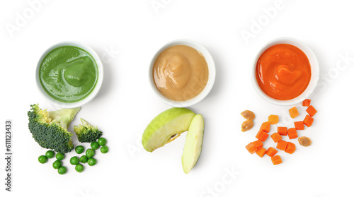Bowls with healthy baby food and fresh vegetables on white background