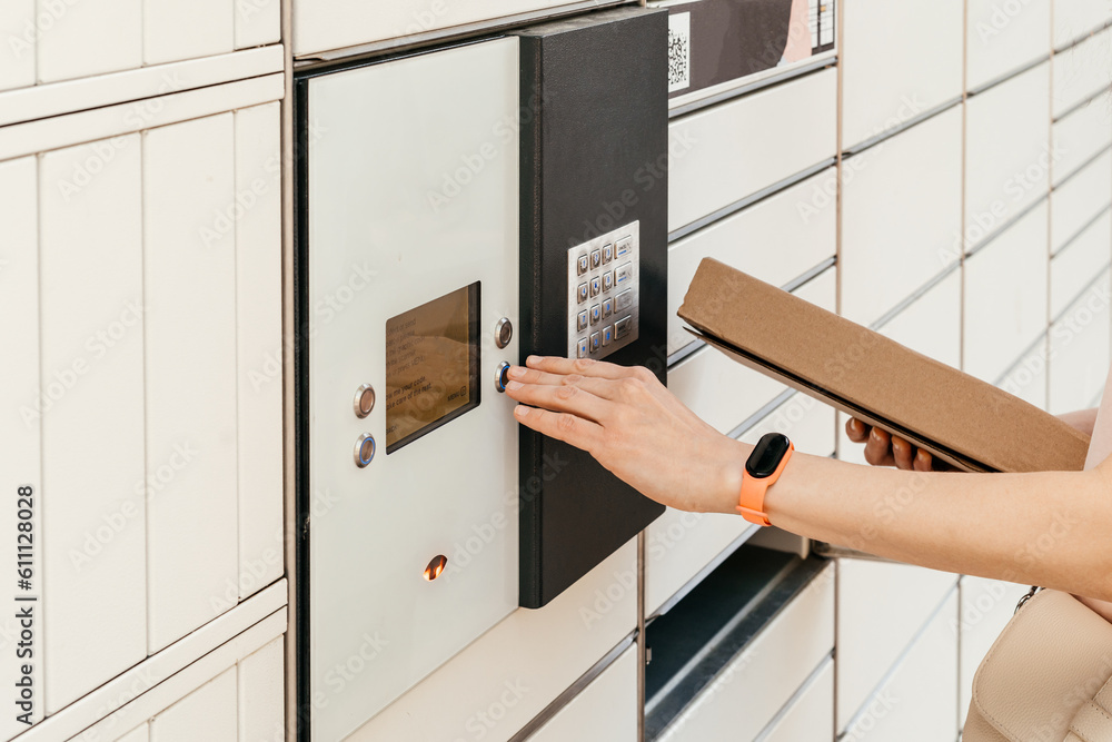 A woman with a box in his hands near the self-service mail terminal. Parcel delivery machine. Person holding a cardboard box. Mail delivery and post service, online shopping, e commerce concept A woman with a box in his hands near the self-service mail terminal. Parcel delivery machine. Person holding a cardboard box. Mail delivery and post service, online shopping, e commerce concept