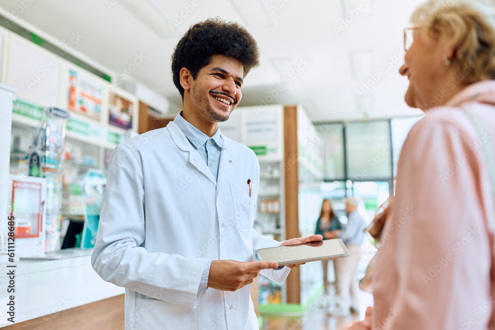 Obraz premium Young happy pharmacist talks to senior woman in drugstore.