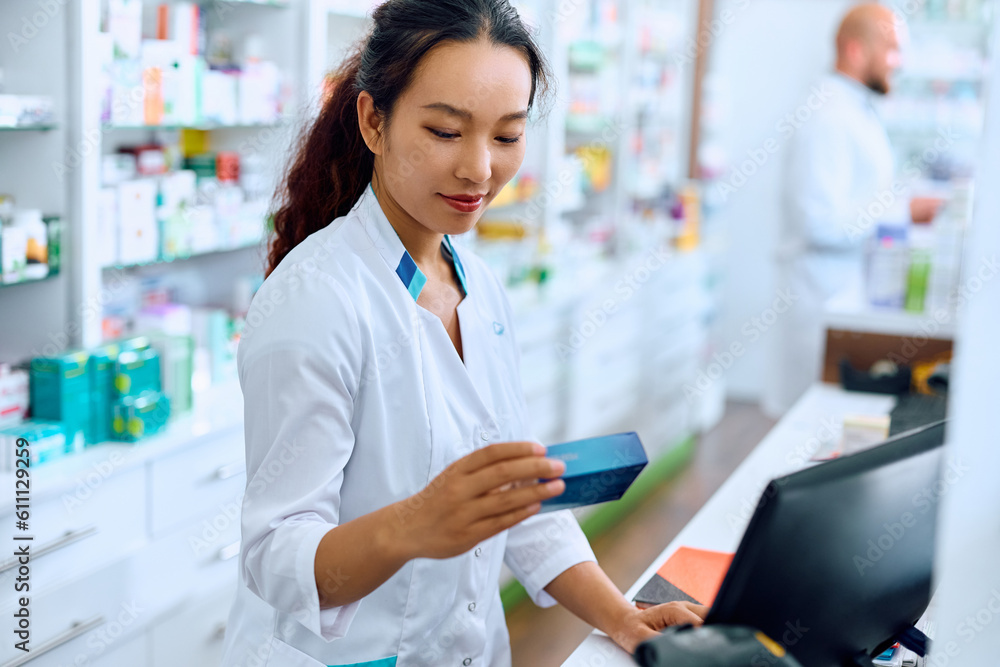 Young Chinese pharmacist working in pharmacy.