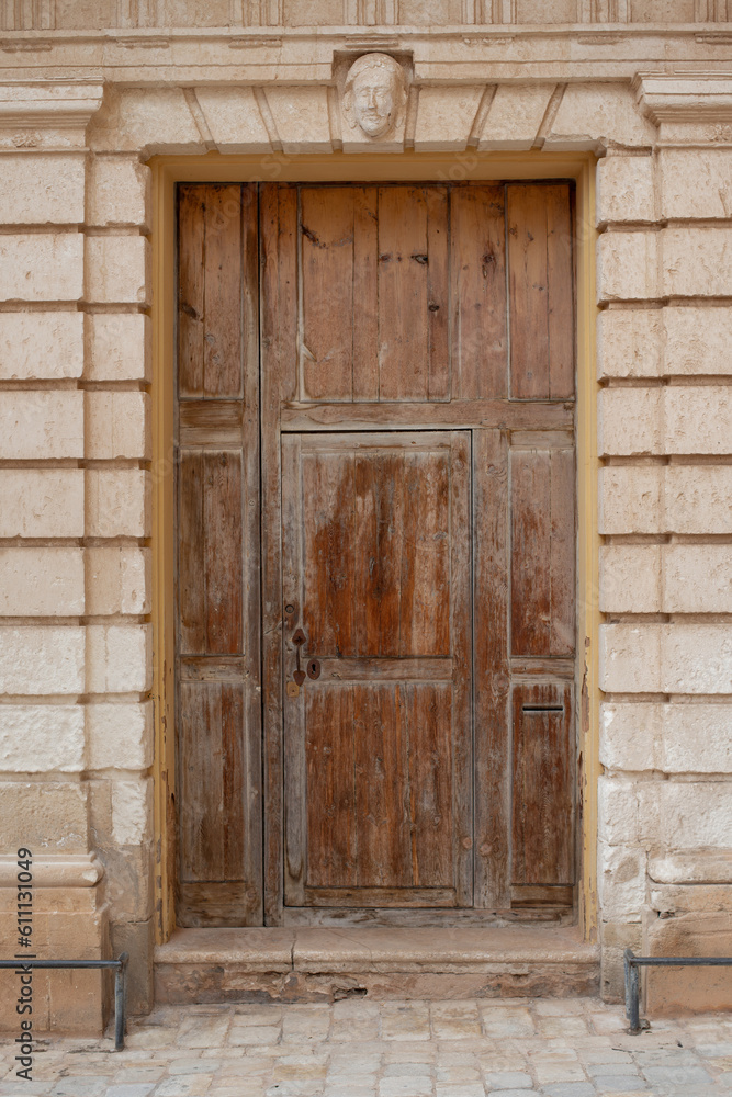 original wooden medieval door in sandstone facade of a historical building on mediterranean island