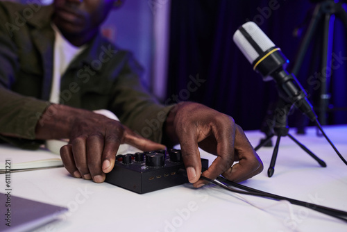 Hands of podcaster inserting cord in amplifier photo