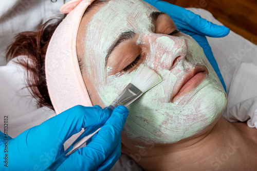 Quadro su tela The cosmetologist applies a collagen booster on the client's face