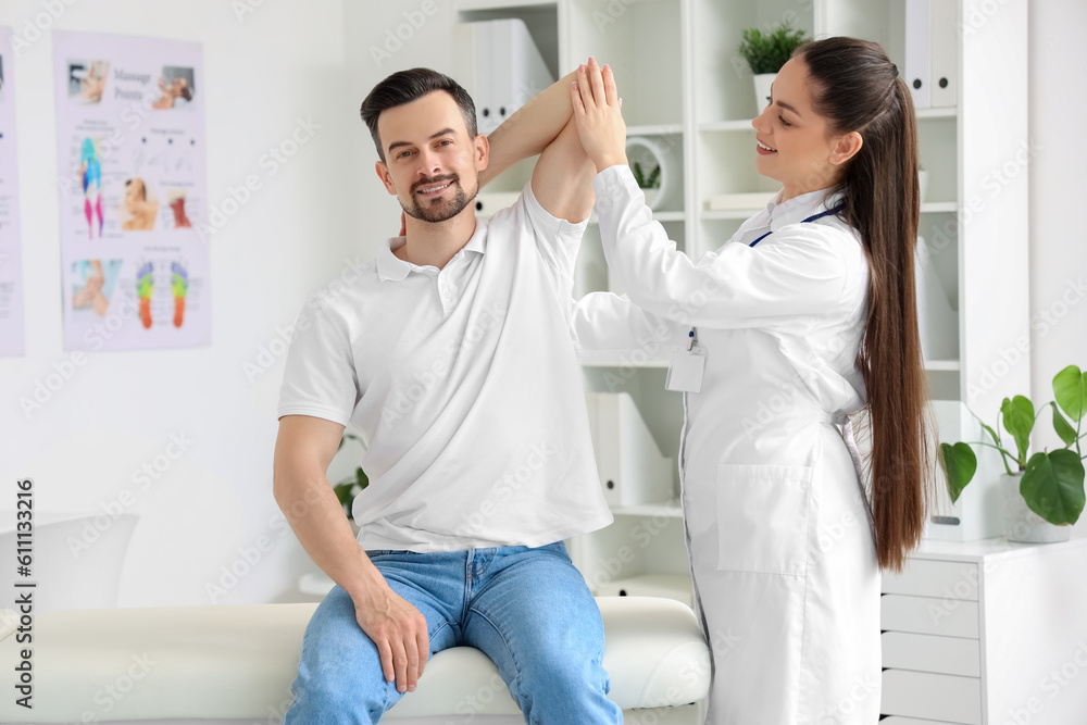 Fototapeta premium Female physiotherapist working with young man in rehabilitation center