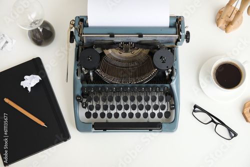 Vintage typewriter with cup of coffee, eyeglasses and hourglass on white background