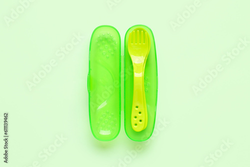 Yellow eating utensils for baby on pale green background