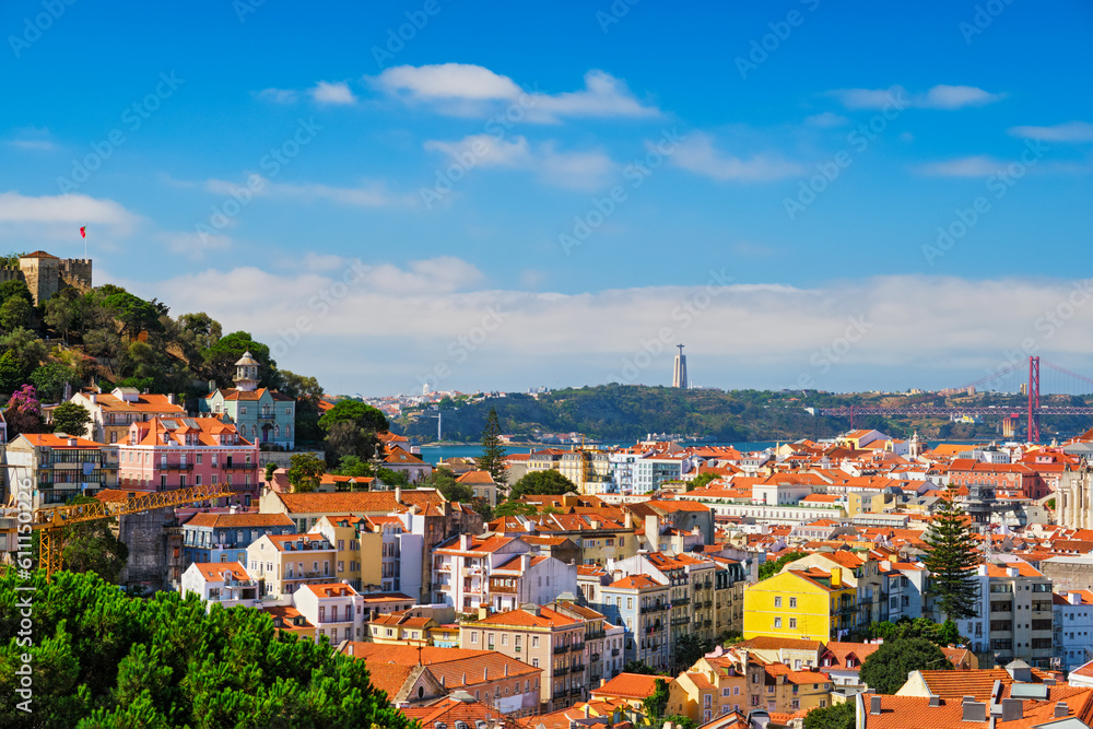 Lisbon famous view from Miradouro dos Barros tourist viewpoint over Alfama old city district with St. George's Castle and Portugal flag, 25th of April Bridge, Christ the King statue. Lisbon, Portugal.