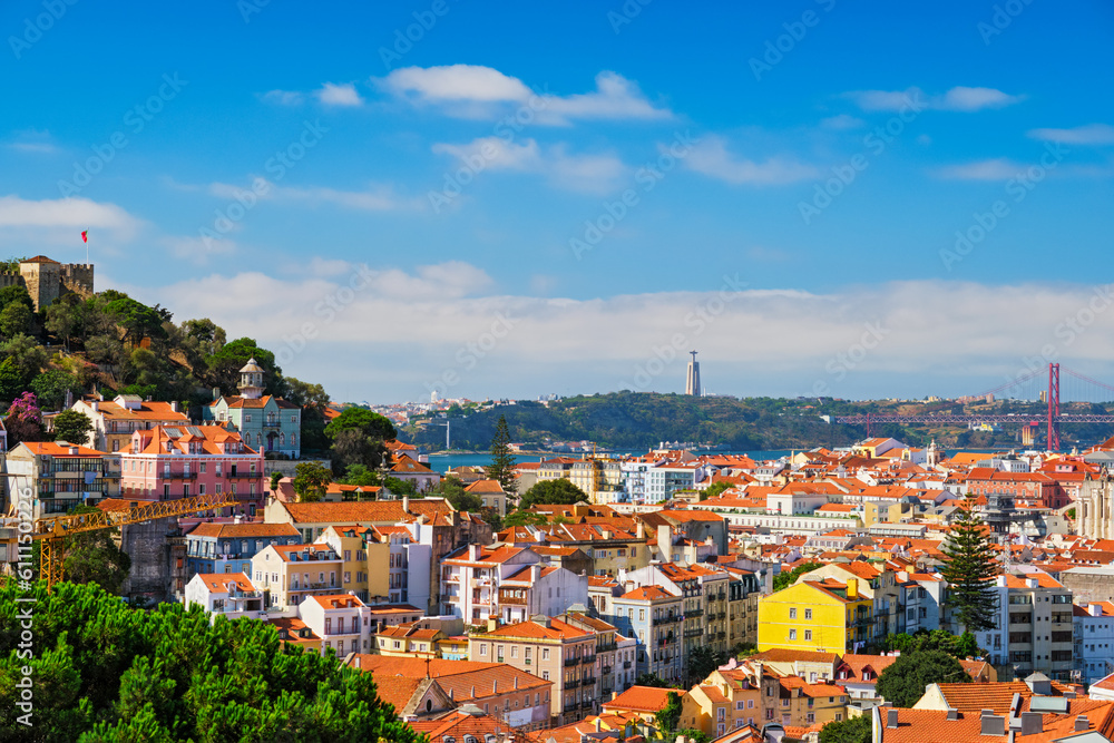 Lisbon famous view from Miradouro dos Barros tourist viewpoint over Alfama old city district with St. George's Castle and Portugal flag, 25th of April Bridge, Christ the King statue. Lisbon, Portugal. Lisbon famous view from Miradouro dos Barros tourist viewpoint over Alfama old city district with St. George's Castle and Portugal flag, 25th of April Bridge, Christ the King statue. Lisbon, Portugal.