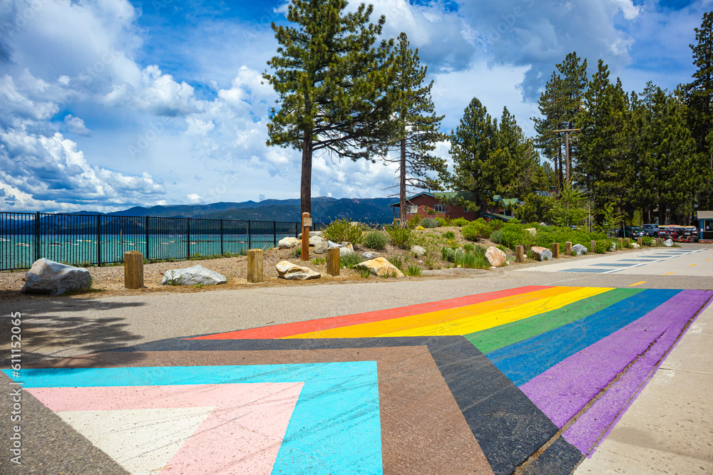 Pride Flag painted on sidewalk in South Lake Tahoe for Pride Month, with view of the South East side of Lake Tahoe