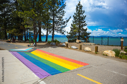 Pride Flag painted on sidewalk in South Lake Tahoe for Pride Month, with view of the South West side of Lake Tahoe and Emerald Bay