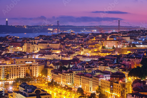 Night view of Lisbon famous view from Miradouro da Senhora do Monte tourist viewpoint of Alfama and Mauraria old city districts, 25th of April Bridge in the evening twilight. Lisbon, Portugal
