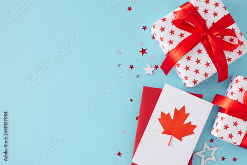 Happy Victoria day celebration idea. Top view flat lay of gift boxes, blank card with red maple leaf and white red stars on light blue background with space for greeting