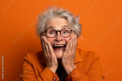 Headshot portrait photography of a glad mature woman putting hands on the face in a gesture of terror against a bright orange background. With generative AI technology © Markus Schröder