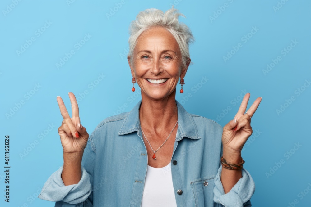 Close-up portrait photography of a happy mature woman making a peace gesture with two fingers against a baby blue background. With generative AI technology Close-up portrait photography of a happy mature woman making a peace gesture with two fingers against a baby blue background. With generative AI technology