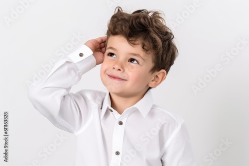 Lifestyle portrait photography of a happy kid male scratching one's head in a gesture of confusion against a pearl white background. With generative AI technology