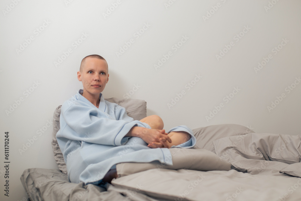 A bald woman in a bathrobe sits in thought on the bed. A bald woman in a bathrobe sits in thought on the bed.