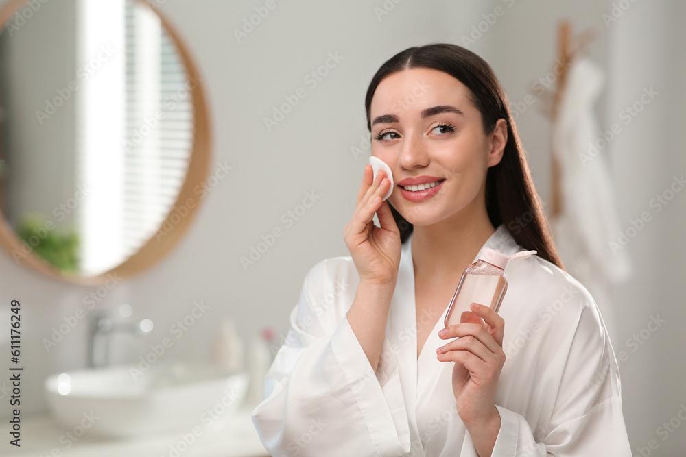 Beautiful woman removing makeup with cotton pad indoors Beautiful woman removing makeup with cotton pad indoors