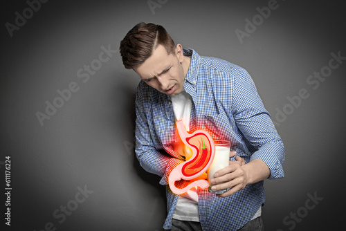 Quadro su tela Man with glass of milk suffering from heartburn on grey background