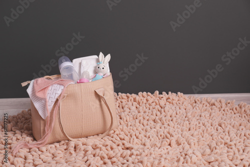 Fototapeta Naklejka Na Ścianę i Meble -  Mother's bag with baby's stuff on rug indoors