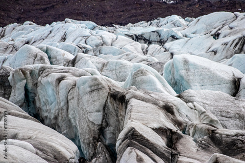 Glacier erosions in Iceland with black volcanic dust on the ice on a cold day in spring, climate crisis