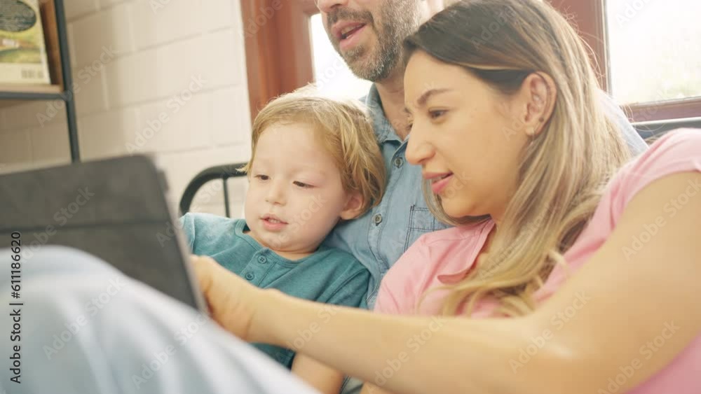 Caucasian parents and little baby son resting on the bed in bedroom with using digital tablet play learning games or watch movie together. Happy family enjoy weekend activity with technology at home. Caucasian parents and little baby son resting on the bed in bedroom with using digital tablet play learning games or watch movie together. Happy family enjoy weekend activity with technology at home.