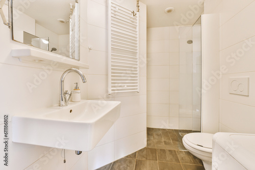 a white bathroom with wood flooring and tile on the walls  along with a walk - in shower stall