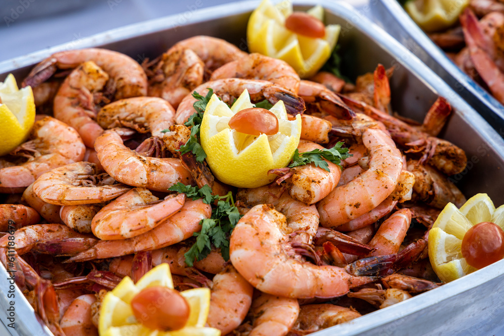 A tray of shrimp served at a buffet with lemon garnish. A tray of shrimp served at a buffet with lemon garnish.