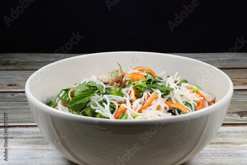Traditional spicy rice noodle salad mixed with fresh herbal vegetable, chilly and crab stick serving in the bowl. Famous appetizer menu dressing with pickled fish sauce in Asia restaurant.