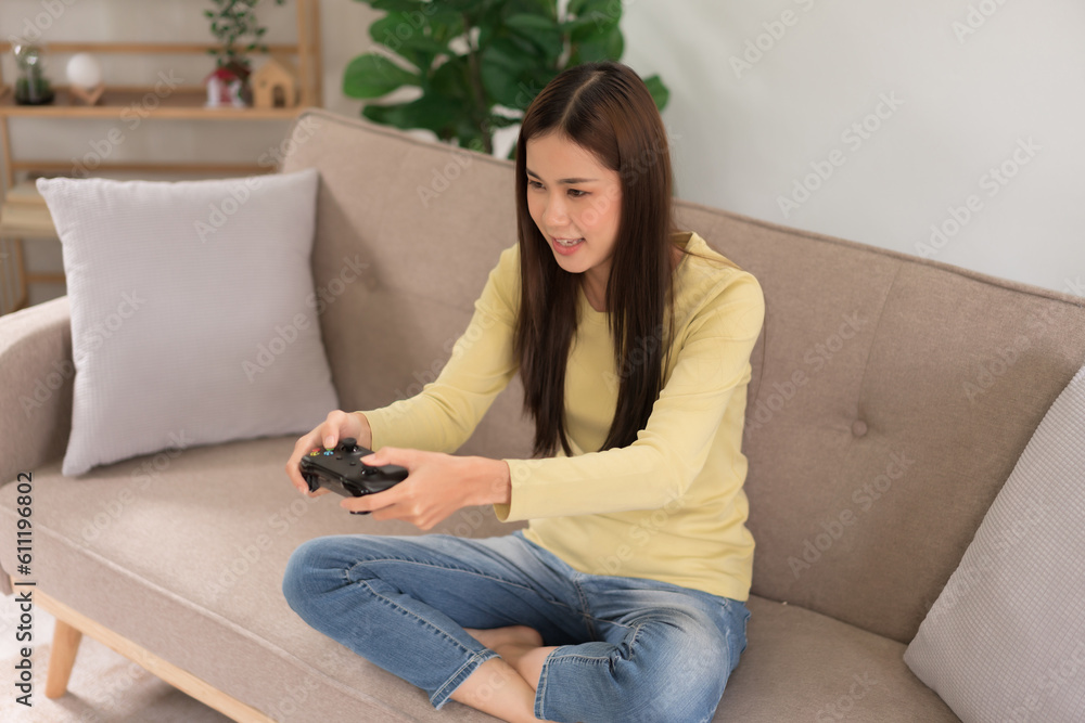 Obraz premium Relaxation concept, Young woman sitting on the couch to control joystick while playing video games