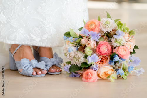 close up of bride's feet in soft blue shoes next to her colorful wedding bouquet filled with spring pastel flowers