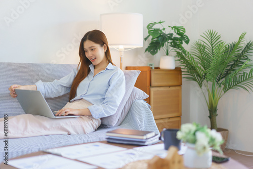 Remote business concept, Businesswoman lying on couch to typing marketing plan report on laptop © Pichsakul