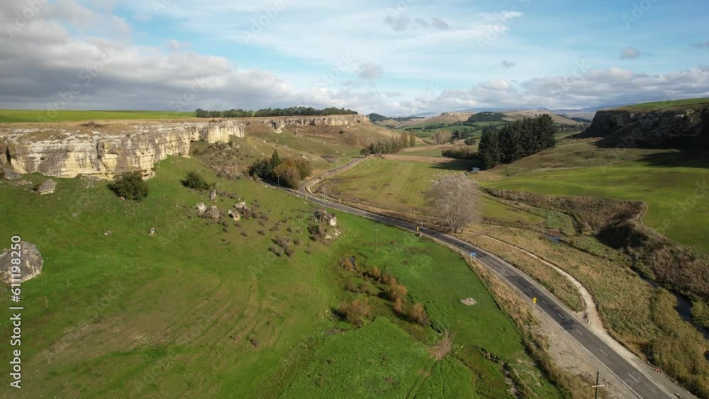 Aerial of scenic road next to limestone cliff in beautiful valley, farmland landscape, New Zealand. Aerial of scenic road next to limestone cliff in beautiful valley, farmland landscape, New Zealand.