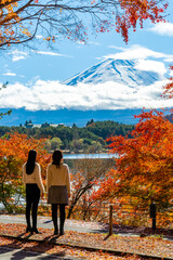 Happy Asian woman friends travel Japan together on autumn holiday vacation. Attractive girl enjoy outdoor lifestyle travel Lake Kawaguchi and Mt Fuji with looking beautiful red maple tree leaf falling