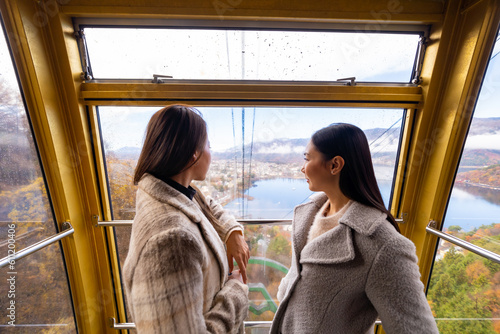 Happy Asian woman friends travel rises to Mt. Fuji on cableway cabin ropeway together on holiday vacation. Attractive girl enjoy outdoor lifestyle travel Lake Kawaguchi and Mt Fuji in autumn season.
